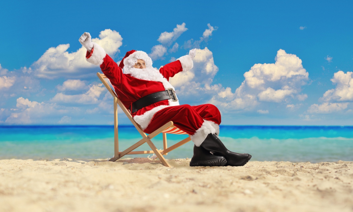 Weihnachtsmann sitzt auf einem Liegestuhl im Sand