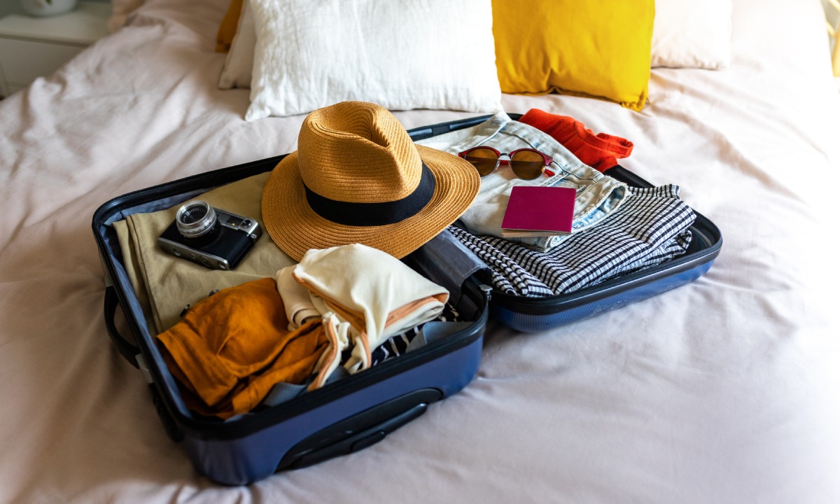 Suitcase with hat, sunglasses, camera and passport