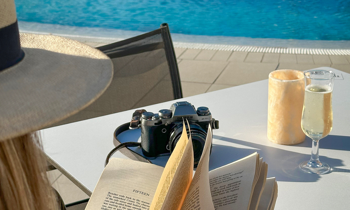 Una mujer leyendo un libro junto a la piscina