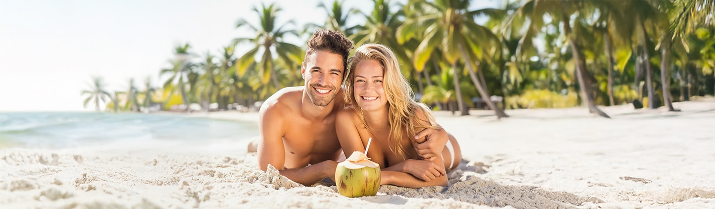 Pareja sonriente tumbada en la arena con coco