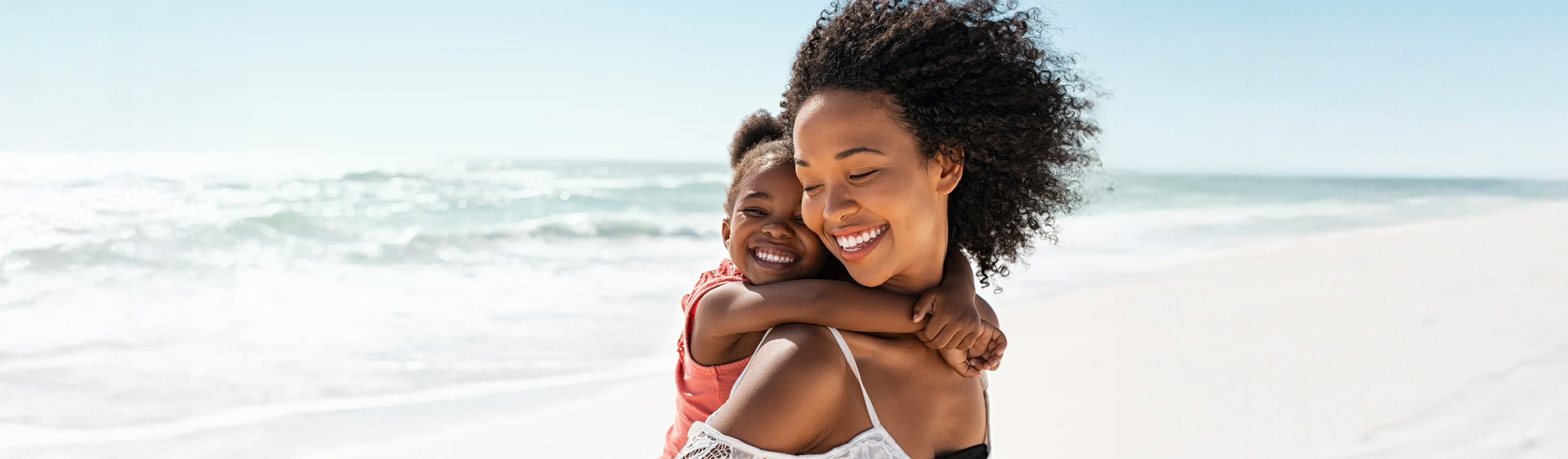 Madre con hija en brazos junto al mar