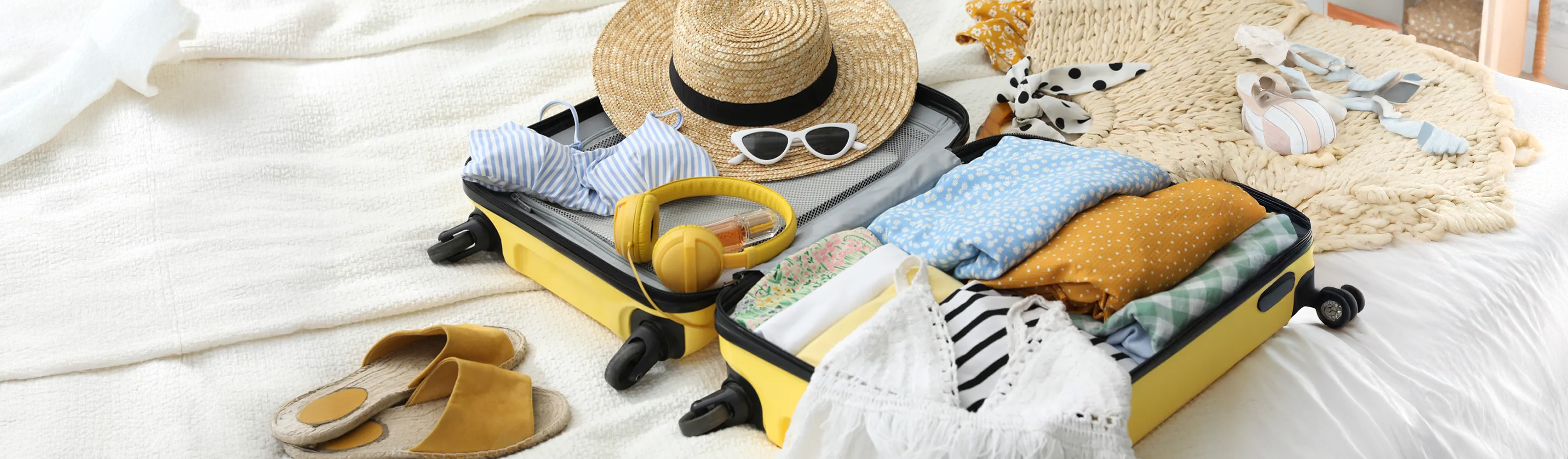 Koffer mit Sommerartikeln auf dem Bett
