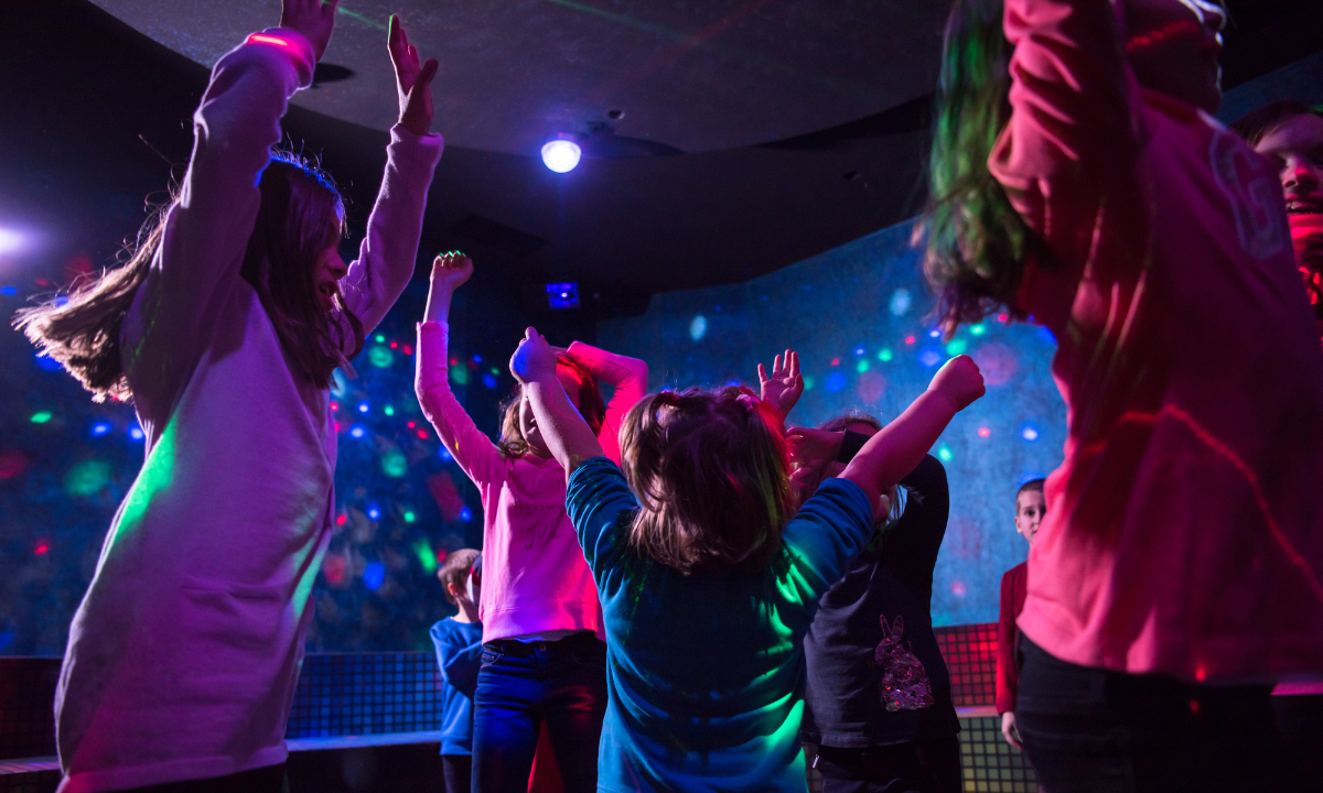 Children dancing at a mini-disco with colourful lights