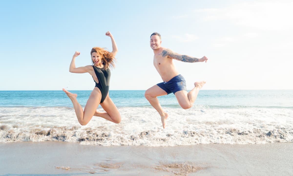 Pareja saltando en la playa
