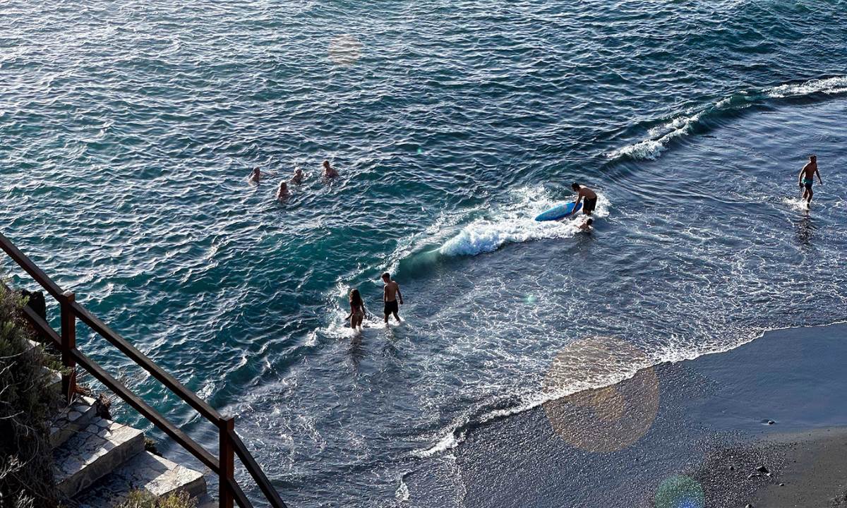 People enjoying the sea and surfing on a black-sand beach in La Palma