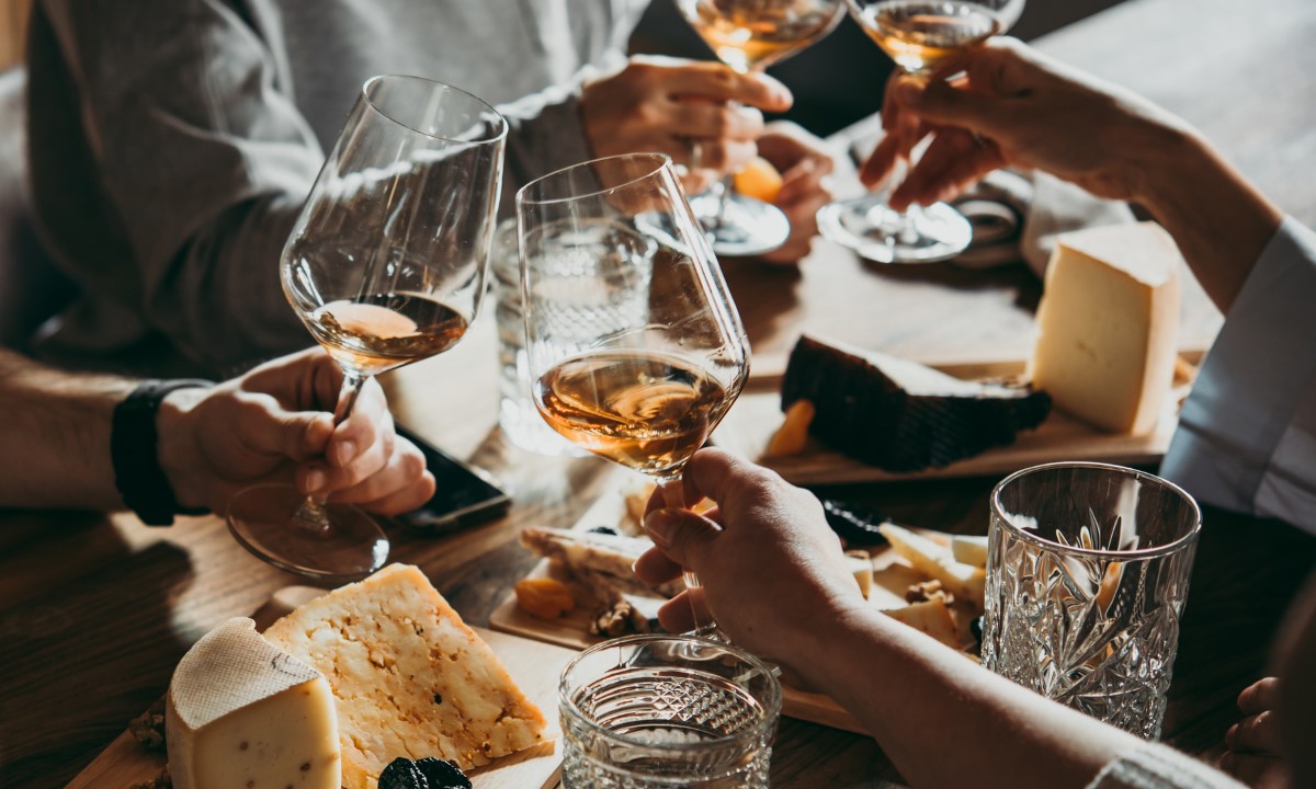 People toasting with white wine alongside a cheese board in a winery in Tenerife
