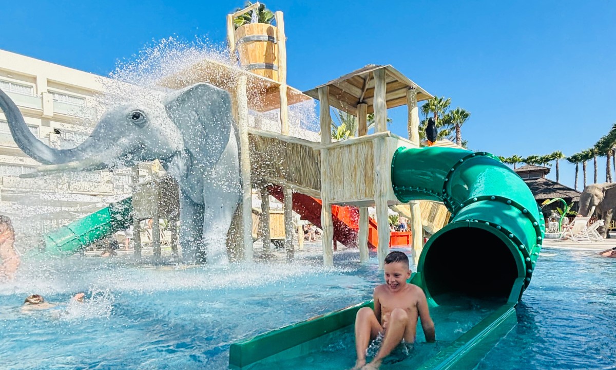 Child sliding down a green slide at the children's water park, Splash Park, at the Maspalomas & Tabaiba Princess hotel.
